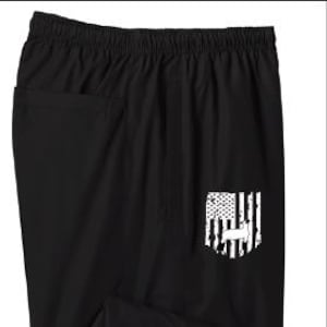 May include: Black athletic pants with an elastic waistband and a small pocket. A white graphic of the American flag and a deer silhouette is on the right leg. The pants have a split at the bottom of the leg.