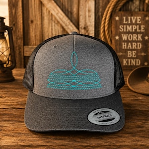May include: A gray trucker hat with a black mesh back and a turquoise embroidered design. The hat features a curved brim and a snapback closure. The hat has a "Snapback" label.