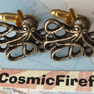 May include: A pair of bronze-colored octopus cufflinks with gold-colored posts. The cufflinks are detailed with intricate tentacle designs. The image includes a Cosmic Firefly label and a map background.
