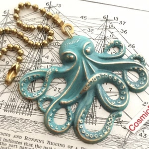 May include: A teal octopus-shaped ceiling fan pull chain with gold accents. The octopus has detailed tentacles and is attached to a gold ball chain. The background features a nautical map.