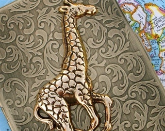 May include: A gold-colored giraffe figurine with a detailed textured surface. The figurine is sitting on a decorative, ornate, gold-colored surface.