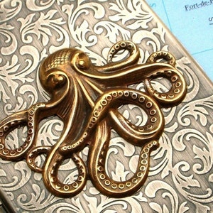 Op de afbeelding: Een bronzen metalen doos met een reli&euml;fontwerp van een octopus. De octopus is verhoogd en gedetailleerd, met zijn tentakels die over het oppervlak krullen. De achtergrond heeft een bloemenpatroon.