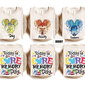 Peut inclure: Six t-shirts en couleur ivoire avec des motifs différents. Trois t-shirts présentent une illustration de style aquarelle d'un personnage du film Vice-Versa. Les trois autres t-shirts présentent le texte "Today is a CORE MEMORY Day" avec une tête de Mickey Mouse de dessin animé et une illustration de style aquarelle des personnages de Vice-Versa.
