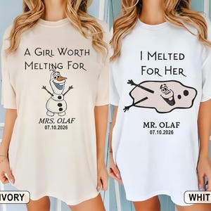 以下が含まれることがあります： 2枚のTシャツ。1枚はアイボリー、もう1枚は白で、アナと雪の女王のオラフが描かれています。アイボリーのシャツには「A Girl Worth Melting For」とオラフが描かれています。白いシャツには「I Melted For Her」と溶けたオラフが描かれています。どちらのシャツにも「Mrs. Olaf」と「Mr. Olaf」と日付が書かれています。