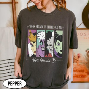 Puede incluir: Camiseta gris oscuro con un gr&aacute;fico de cuatro villanos de dibujos animados en paneles coloridos. El texto de arriba dice "WHO'S AFRAID OF LITTLE OLD ME" y debajo "YOU SHOULD BE". La camiseta tiene un corte holgado y est&aacute; etiquetada como "PEPPER" en la parte inferior.