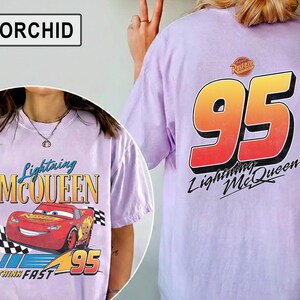 Pu&ograve; includere: T-shirt lilla con design di Lightning McQueen. La parte anteriore mostra l'auto e il testo "Lightning McQueen" e "95". Il retro presenta una grande grafica "95" con "Lightning McQueen" sotto. Una maglietta casual.