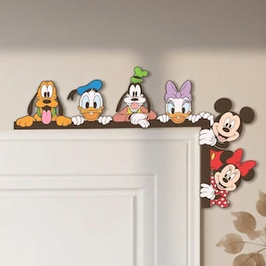 Può includere: Un adesivo murale decorativo per l'angolo di una porta con personaggi dei cartoni animati colorati, tra cui Pluto, Paperino, Pippo, Paperina, Topolino e Minnie. I personaggi sono disposti lungo il bordo superiore e laterale di una porta.