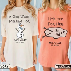 以下が含まれることがあります： 2枚のTシャツ。1枚はアイボリー、もう1枚はテラコッタで、アナと雪の女王のオラフが描かれています。アイボリーのシャツには「A Girl Worth Melting For」とオラフが描かれています。テラコッタのシャツには「I Melted For Her」と溶けたオラフが描かれています。どちらのシャツにも「Mrs. Olaf 07.10.2026」と「Mr. Olaf 07.10.2026」と書かれています。