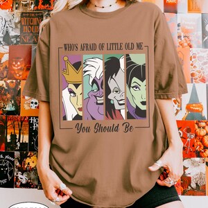 Puede incluir: Camiseta color espresso con un gr&aacute;fico de cuatro villanos de dibujos animados y el texto "WHO'S AFRAID OF LITTLE OLD ME - You Should Be." El dise&ntilde;o incluye a la Reina Malvada, &Uacute;rsula, Cruella de Vil y Mal&eacute;fica. La camiseta tiene un corte holgado y oversize.