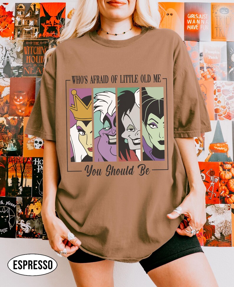 Puede incluir: Camiseta color espresso con un gr&aacute;fico de cuatro villanos de dibujos animados y el texto "WHO'S AFRAID OF LITTLE OLD ME - You Should Be." El dise&ntilde;o incluye a la Reina Malvada, &Uacute;rsula, Cruella de Vil y Mal&eacute;fica. La camiseta tiene un corte holgado y oversize.
