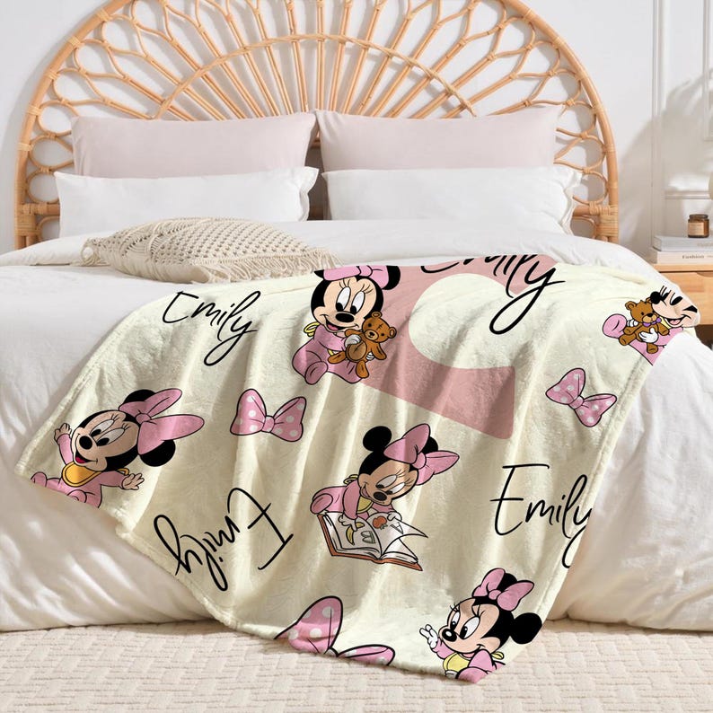 May include: A cream-colored blanket featuring Minnie Mouse illustrations in pink and black, with the name "Emily" in script. The blanket has a large pink letter "E" and pink polka dots.