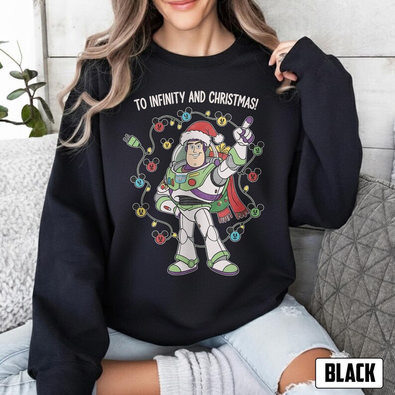 May include: Black sweatshirt with a festive graphic of Buzz Lightyear wearing a Santa hat and Christmas lights. The text "TO INFINITY AND CHRISTMAS!" is printed above the character. The word "BLACK" is in a white rectangle at the bottom.