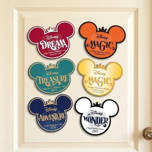 May include: Six Mickey Mouse-shaped magnets featuring Disney cruise ship names and voyage details. The magnets are red, orange, teal, gold, navy, and white, each topped with a small crown icon and printed with specific cruise dates and locations.