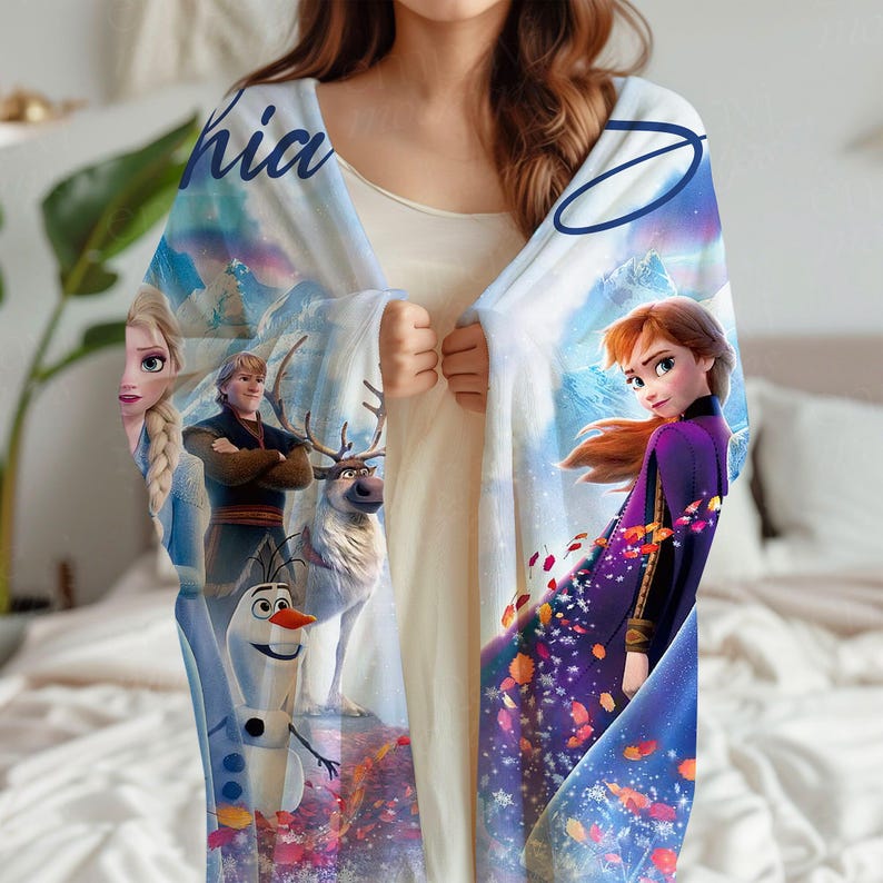 K&ouml;nnte beinhalten: Eine hellblaue Decke mit Figuren aus dem Animationsfilm "Die Eisk&ouml;nigin". Die Decke zeigt Elsa, Anna, Kristoff, Olaf und Sven vor dem Hintergrund schneebedeckter Berge und fallender Bl&auml;tter. Das Wort "hia" ist sichtbar.