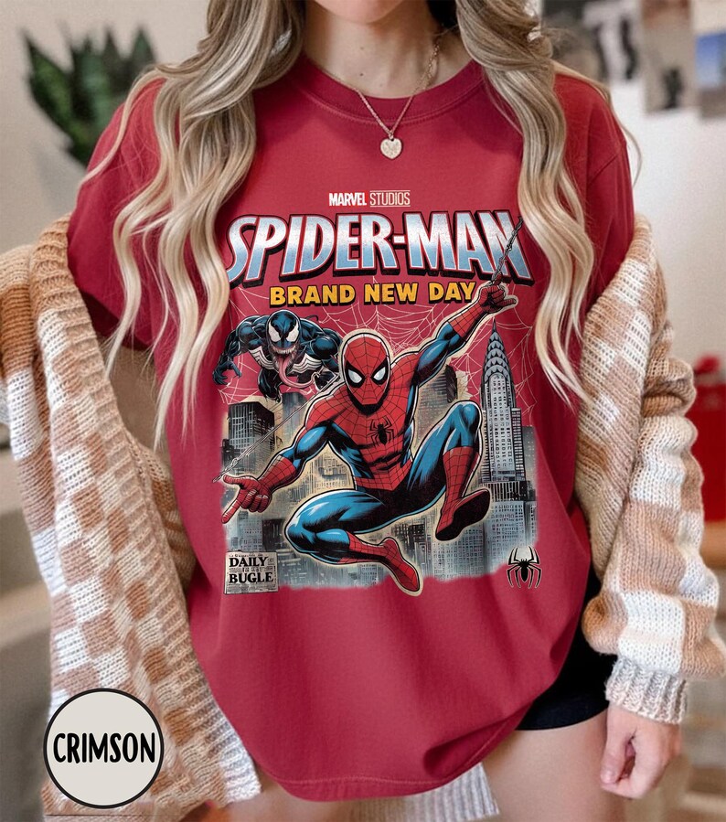 K&ouml;nnte beinhalten: Karmesinrotes T-Shirt mit einem Spider-Man-Motiv von Marvel Studios. Das Design zeigt Spider-Man in Aktion, den Text "SPIDER-MAN BRAND NEW DAY" und das Daily Bugle-Logo. Das T-Shirt hat einen Rundhalsausschnitt und kurze &Auml;rmel.
