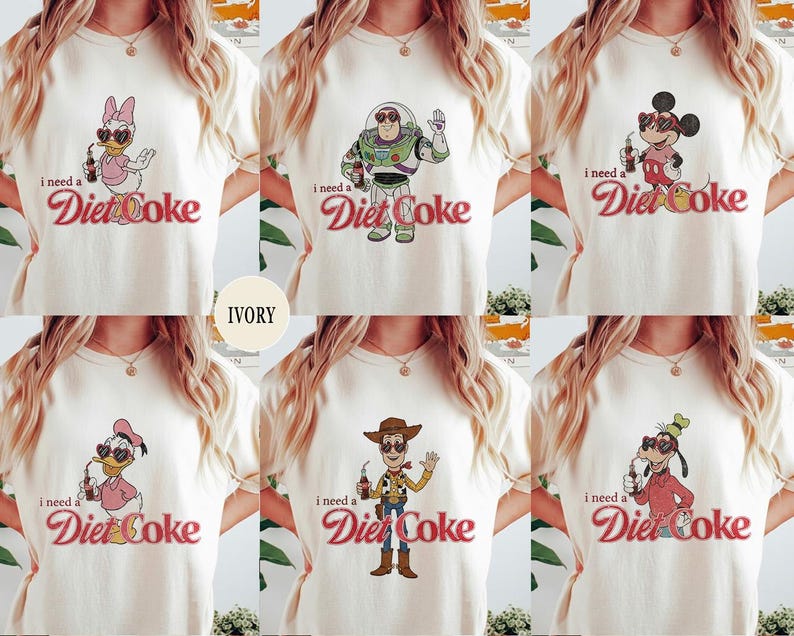K&ouml;nnte beinhalten: Elfenbeinfarbene T-Shirts mit Cartoon-Charakteren und dem Text "I need a Diet Coke." Designs umfassen Daisy Duck, Buzz Lightyear, Mickey Mouse, Donald Duck, Woody und Goofy. Der Text "Diet Coke" ist in Schreibschrift.
