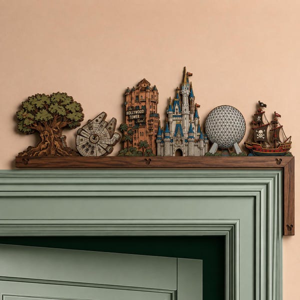 May include: A dark wood mantel shelf featuring layered wooden cutouts of iconic theme park landmarks, including a large tree, a spaceship, the Hollywood Tower Hotel, a blue castle, a geodesic sphere, and a pirate ship with a skull flag.