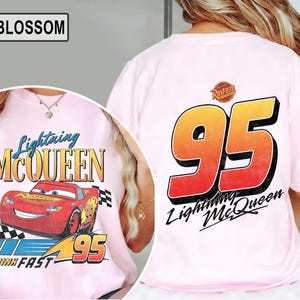 Pu&ograve; includere: T-shirt rosa chiaro con Lightning McQueen del film Cars. La parte anteriore presenta il personaggio e il testo, mentre il retro mostra un grande "95" e il testo "Lightning McQueen". La maglietta ha anche il testo "Think Fast".