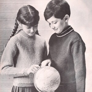 Puede incluir: Dos niños, una niña con trenzas y un niño, están mirando un globo terráqueo. La niña lleva un suéter marrón claro y una falda oscura. El niño lleva un suéter azul oscuro con una franja blanca alrededor del cuello. El globo está sobre un soporte negro.