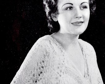 May include: A woman wearing a white lace shawl with a delicate pattern. The shawl is draped over her shoulders and tied at the front. She is wearing a white blouse underneath.