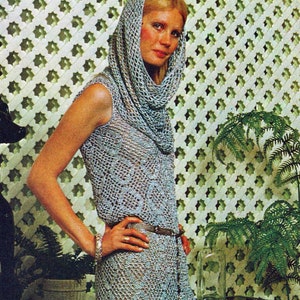 May include: A woman wearing a long, silver crochet dress with a matching hood. She is standing in front of a patterned wall and holding her hand on her hip.