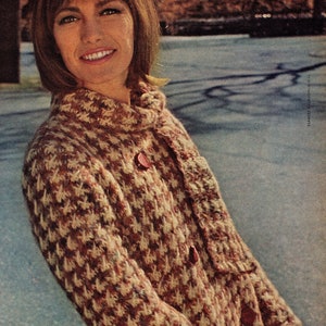 May include: A brown and white houndstooth patterned knitted coat with red buttons. The coat is worn by a woman with brown hair and is shown from the waist up.