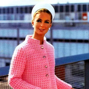 May include: A pink knitted cardigan with a waffle stitch pattern and button closures. The cardigan is worn by a woman with a white headband and pearl earrings.