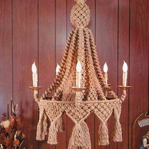 May include: A macrame chandelier with five light bulbs and tassels hanging from the bottom. The chandelier is made of natural fiber rope and has a brown color.