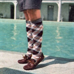 May include: A person wearing argyle knee-high socks in white, black, and burgundy, paired with brown leather loafers. The socks have a classic diamond pattern. The loafers have a bow detail.