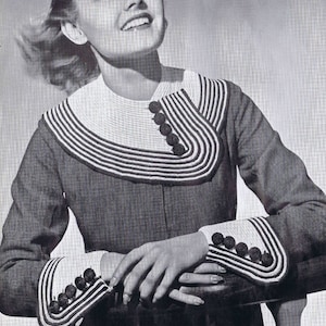 May include: A black and white striped sweater with a large collar and cuffs. The collar and cuffs are trimmed with white and have black buttons.