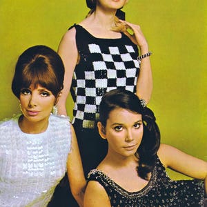 May include: Three women wearing sequined tops. The woman in the center is wearing a black and white checkered top. The woman on the left is wearing a white top with sequins. The woman on the right is wearing a black top with sequins.