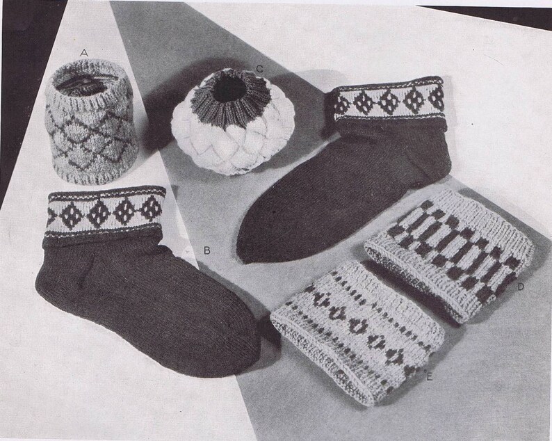 K&ouml;nnte beinhalten: F&uuml;nf gestrickte Artikel, darunter Socken, eine M&uuml;tze und Beinstulpen, mit verschiedenen geometrischen Mustern in Schwarz und Wei&szlig;.
