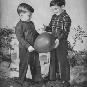 May include: Two young boys, one wearing a plaid shirt and the other a knitted sweater, stand together holding a red balloon. The boy in the plaid shirt is holding the balloon and smiling.