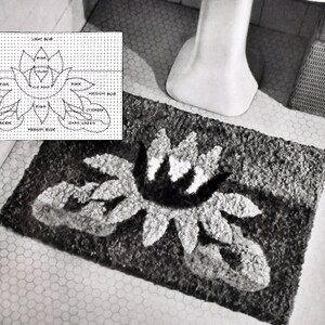 May include: A black and white bath mat with a stylised flower design. The mat is made of a fluffy, textured material. The design includes light blue, pink, and green colours.
