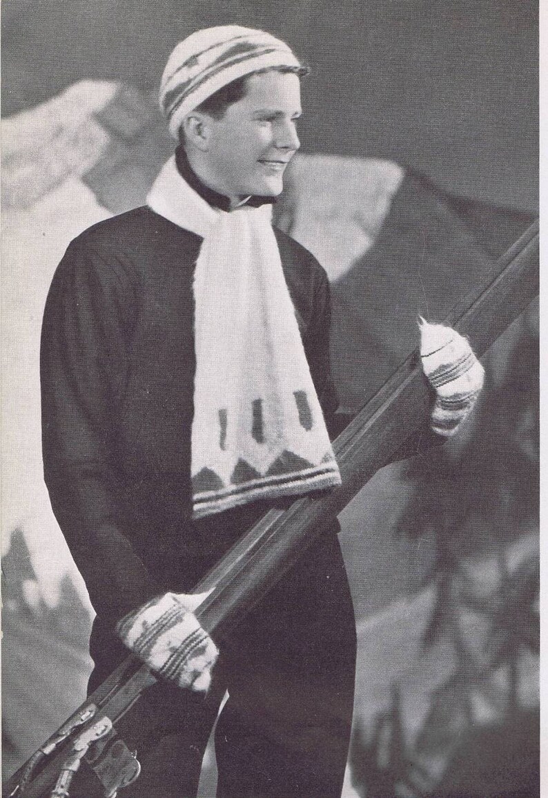 K&ouml;nnte beinhalten: Ein Schwarzwei&szlig;foto einer Person, die eine wei&szlig;e Strickm&uuml;tze und einen Schal mit geometrischem Muster tr&auml;gt. Die Person h&auml;lt ein Paar Ski.