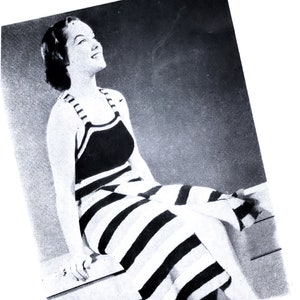 Könnte beinhalten: Ein schwarz-weiß gestreifter Badeanzug mit einem Neckholder-Oberteil. Der Badeanzug wird von einer Frau getragen, die den Kopf nach hinten geneigt hat und nach oben schaut.