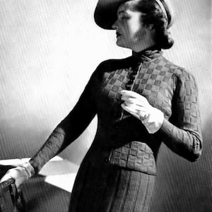 Peut inclure: Photographie en noir et blanc d'une femme portant un ensemble élégant d'époque. La tenue comprend un chapeau à bord incurvé, une veste à carreaux et une longue jupe. Elle porte également des gants blancs.