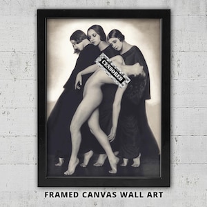 May include: Black and white framed canvas wall art featuring a vintage photograph of three figures. Two figures in long black dresses support a nude figure, with a censored area. The text "FRAMED CANVAS WALL ART" is at the bottom.