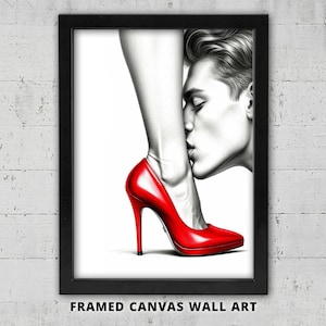 May include: Framed canvas wall art featuring a black and white illustration of a person's face kissing a leg wearing a bright red high heel shoe. The art is framed in a black frame and is displayed against a white brick wall.