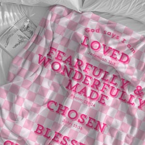 Puede incluir: Manta de tiro a cuadros rosa y blanca con el texto "God says I am LOVED Jeremiah 31:3 FEARFULLY & WONDERFULLY MADE Psalm 139:14 CHOSEN John 15:16 BLESSED"