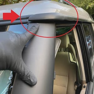 Könnte beinhalten: Nahaufnahme der Dachlinie eines Fahrzeugs, die eine schwarze Zierleiste und ein silberfarbenes Dach zeigt. Das Bild hebt die Kante des Daches und die angrenzende Säule hervor, mit einer Hand in einem schwarzen Handschuh, die auf die Zierleiste zeigt.