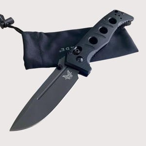 May include: A black folding knife with a textured handle and a butterfly logo. The knife comes with a black pouch.