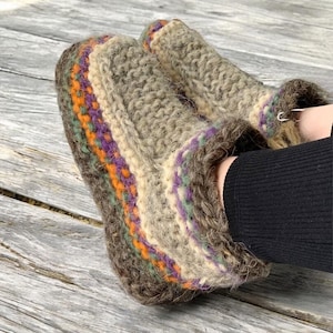 May include: A pair of brown knitted wool slippers with colorful stripes around the top edge. The slippers are made of a soft, fuzzy material and have a comfortable fit.