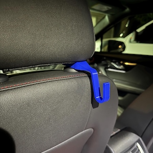 May include: A blue plastic hook designed to hang items from the back of a car seat.