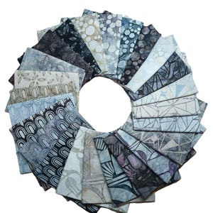 May include: A circular arrangement of fabric squares in various shades of blue, gray, and beige. Each square features a unique pattern, including leaf, geometric, and abstract designs. The fabrics are neatly folded and arranged to create a visually appealing display.