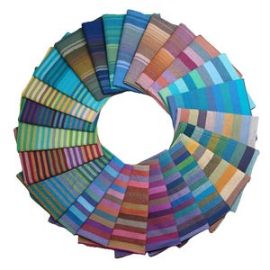 May include: A circular arrangement of folded, striped fabric napkins in various colors. The napkins are arranged in a radial pattern, showcasing a spectrum of hues including blues, greens, reds, and purples. Each napkin features a distinct striped design.