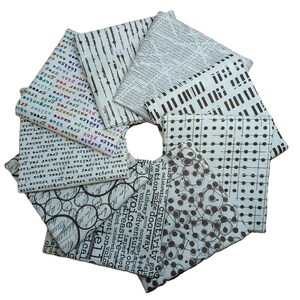 May include: A collection of fabric squares arranged in a circular pattern. The fabrics feature various patterns, including lines, dots, and text. Colors include white, black, and shades of brown. The fabrics are likely for quilting or crafting projects.