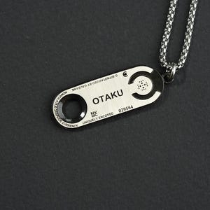 May include: Silver necklace with a silver pendant that says "OTAKU" and has a unique code. The pendant is attached to a silver chain.