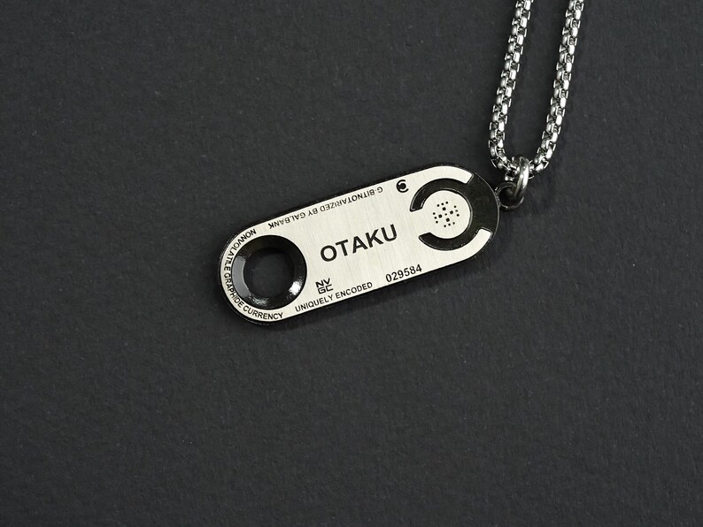May include: Silver necklace with a silver pendant that says "OTAKU" and has a unique code. The pendant is attached to a silver chain.