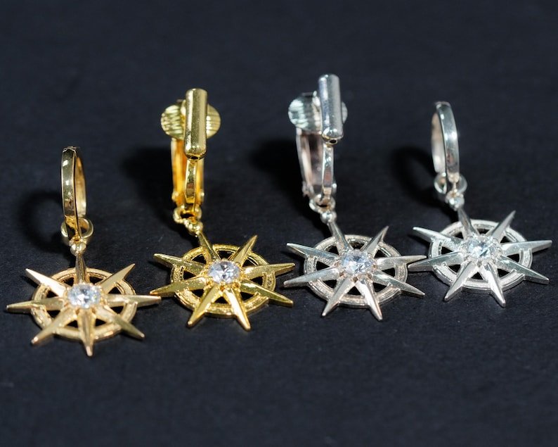 K&ouml;nnte beinhalten: Vier goldene und silberne Ohrclips mit einem Sternendesign und einem klaren Strassstein in der Mitte.